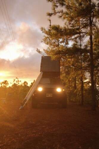 a view of sunset and camping truck surrounded between trees