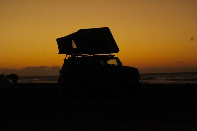 jeep with rooftop tent on a sunset site