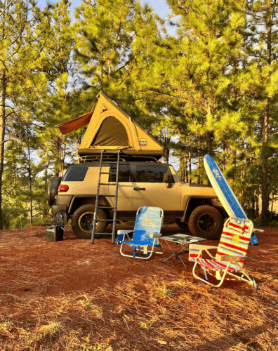 yellow jeep with rooftop tent and folding chairs