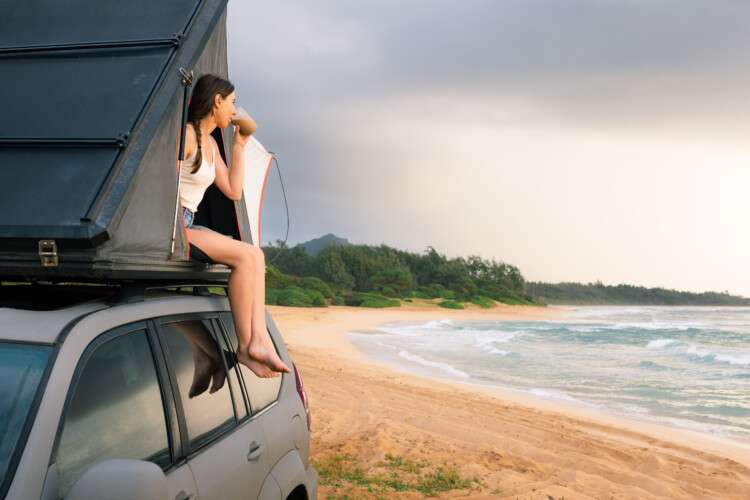 girl enjoying coffee mug while sitting on the rooftop tent