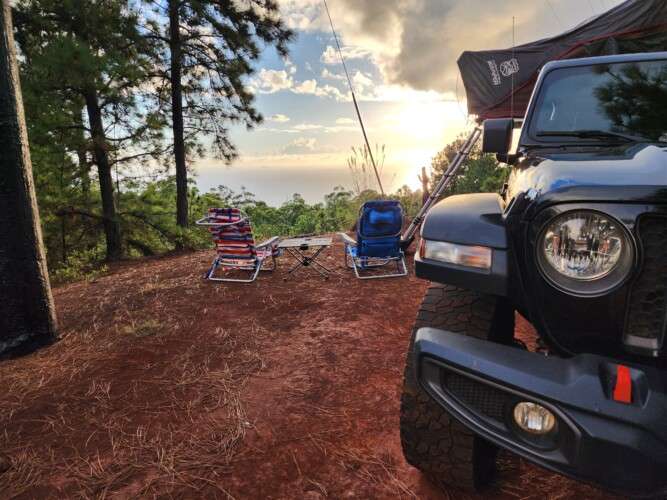 black jeep with foldable chairs on camping site