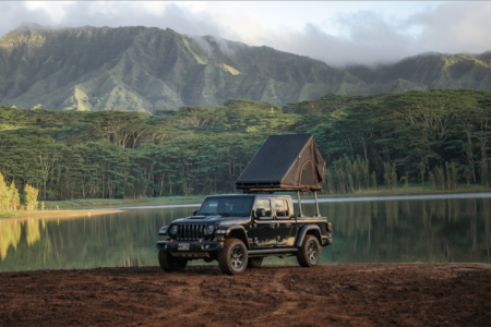 black jeep standing infront of lake surrounded trees and mountains